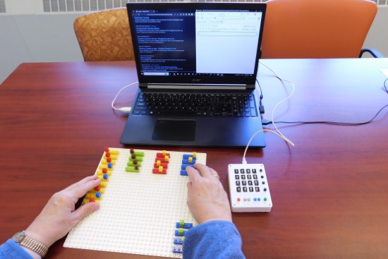 Photo of visually impaired user using tangible tools to interact with computer